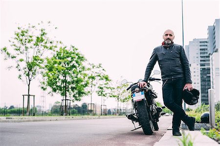 Portrait of mature male motorcyclist leaning on motorcycle Stock Photo - Premium Royalty-Free, Code: 649-08714732