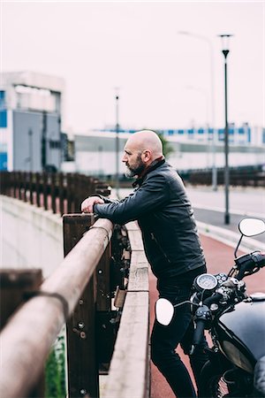 Mature male motorcyclist looking out from roadside railing Stock Photo - Premium Royalty-Free, Code: 649-08714747