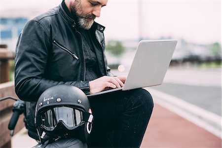 Mature male motorcyclist on roadside using laptop Stock Photo - Premium Royalty-Free, Code: 649-08714749