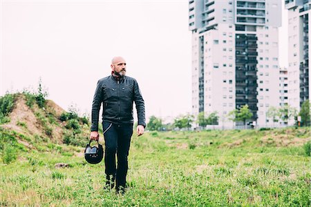 Mature male motorcyclist walking on wasteland holding helmet Stock Photo - Premium Royalty-Free, Code: 649-08714741