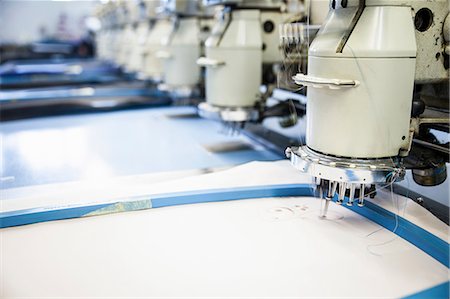 factory and closeup - Rows of programmed embroidery machines speed stitching white cloth in clothing factory Stock Photo - Premium Royalty-Free, Code: 649-08714902