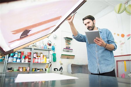 printer of man at work - Male printer preparing paper and silkscreen in printing press studio Stock Photo - Premium Royalty-Free, Code: 649-08714925