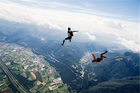 Freestyle skydiving team training together. One man  performing air-ballet, another jumper is filming with video camera on helmet, Locarno, Tessin, Switzerland Stock Photo - Premium Royalty-Free, Code: 649-08714986