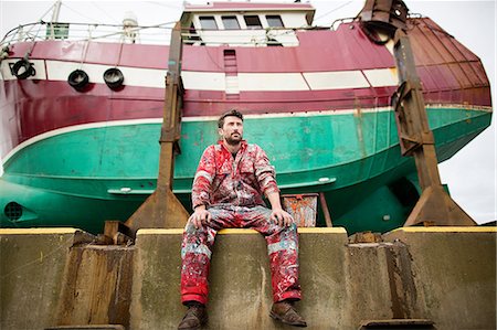 fishing boats scotland - Male ship painter sitting in front of fishing boat on drydock Stock Photo - Premium Royalty-Free, Code: 649-08715022