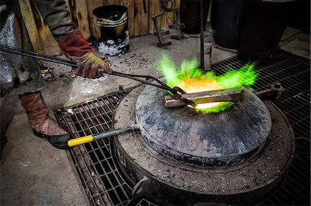 Male foundry worker heating bronze ingot over furnace in bronze foundry Stock Photo - Premium Royalty-Free, Code: 649-08715034
