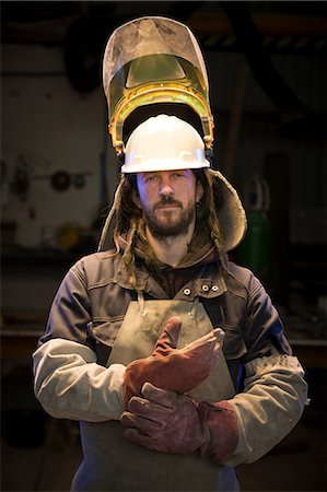 Portrait of mid adult male foundry worker putting on protective gloves in bronze foundry Photographie de stock - Premium Libres de Droits, Code: 649-08715039
