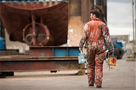 Rear view of male ship painter carrying paint cans in ship painters yard Foto de stock - Sin royalties Premium, Código: 649-08715031