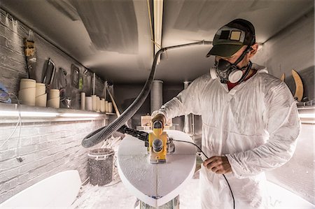 dust (dry particles) - Male carpenter using sander on surfboard in surfboard maker's workshop Foto de stock - Sin royalties Premium, Código: 649-08715048