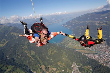 Smiling tandem sky divers holding hand with free faller, Interlaken, Berne, Switzerland Photographie de stock - Premium Libres de Droits, Code: 649-08715053