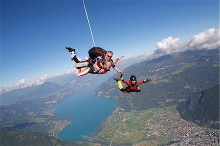 Smiling tandem sky divers holding hand with free faller, Interlaken, Berne, Switzerland Stock Photo - Premium Royalty-Free, Code: 649-08715062