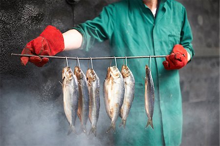 pescadero - Man in smokehouse holding fish on stick Foto de stock - Sin royalties Premium, Código: 649-08715079
