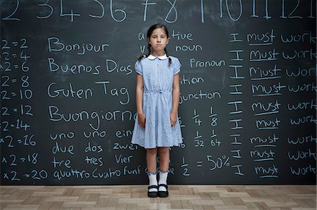 sad kids school uniform - Portrait of schoolgirl standing in front of large chalkboard with schoolwork chalked on it Stock Photo - Premium Royalty-Free, Code: 649-08744887
