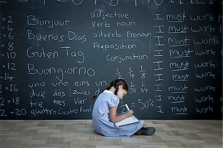 simsearch:614-02640663,k - Schoolgirl sitting studying in front of large chalkboard with schoolwork chalked on it Stock Photo - Premium Royalty-Free, Code: 649-08744888