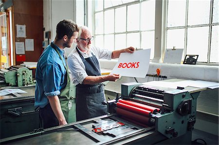 Senior craftsman/technician showing young man letterpress print in book arts workshop Photographie de stock - Premium Libres de Droits, Code: 649-08744891