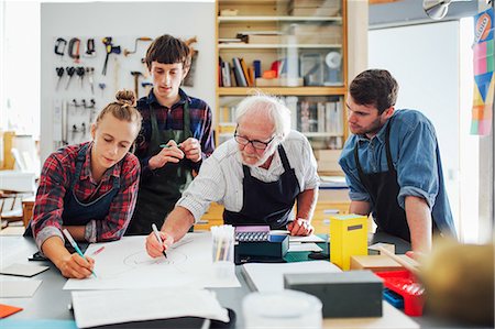 Senior male craftsman brainstorming ideas with group of young men and women in book arts workshop Photographie de stock - Premium Libres de Droits, Code: 649-08744905