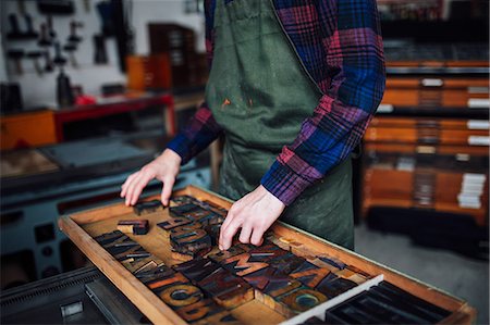 Crop of young craftsman looking through tray of wooden letterpress letters in print workshop Fotografie stock - Premium Royalty-Free, Codice: 649-08744912