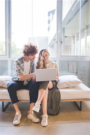 Co-workers working on laptop on sofa by window Foto de stock - Sin royalties Premium, Código: 649-08745049