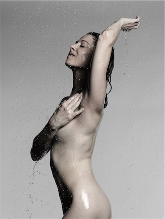 Naked mature woman showering with hand on chest and arm raised Stock Photo - Premium Royalty-Free, Code: 649-08745144