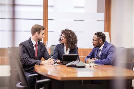 Young businesswoman and two businessmen brainstorming at boardroom table Stock Photo - Premium Royalty-Free, Code: 649-08745299