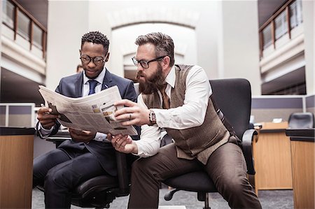 Two businessmen reading broadsheet newspaper in office Stock Photo - Premium Royalty-Free, Code: 649-08745314