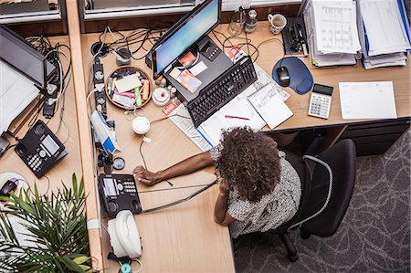 Overhead view of businesswoman talking on landline at office desk Stock Photo - Premium Royalty-Free, Code: 649-08745332