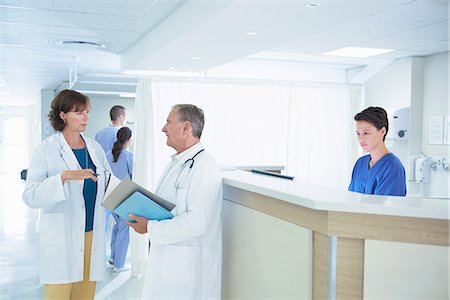 simsearch:649-07709929,k - Male and female doctors discussing medical notes at hospital nurses station Stock Photo - Premium Royalty-Free, Code: 649-08745364