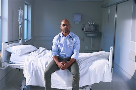 Portrait of mature male doctor sitting on hospital bed in ward Photographie de stock - Premium Libres de Droits, Code: 649-08745394