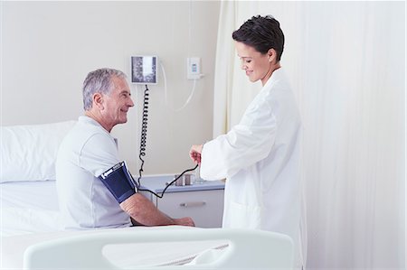 simsearch:649-08745407,k - Female doctor using blood pressure gauge and timing pulse of senior male patient Stock Photo - Premium Royalty-Free, Code: 649-08745401