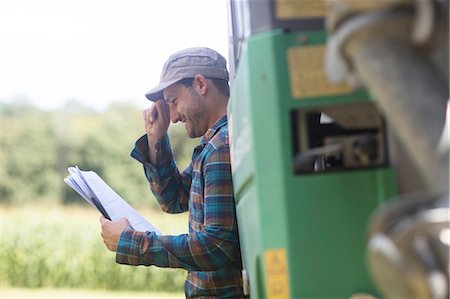 Man leaning against truck looking at paperwork smiling Stock Photo - Premium Royalty-Free, Code: 649-08745424