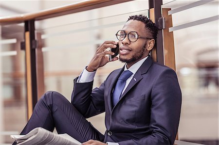 financial page - Businessman sitting on floor chatting on smartphone on office balcony Stock Photo - Premium Royalty-Free, Code: 649-08745614