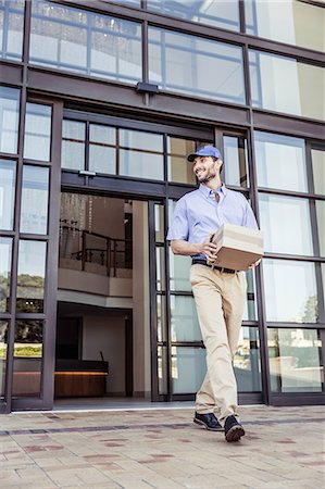 Delivery man carrying package outside office Stock Photo - Premium Royalty-Free, Code: 649-08745619