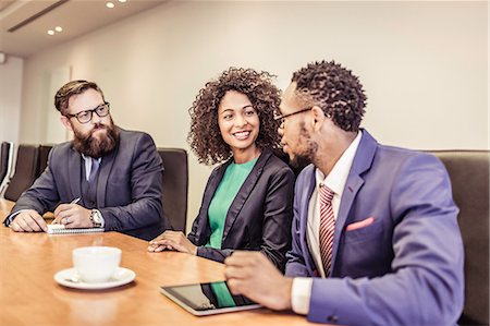 simsearch:649-08968780,k - Young businesswoman talking at conference table meeting with businessmen Foto de stock - Royalty Free Premium, Número: 649-08745621