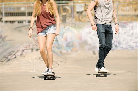 simsearch:614-09159593,k - Neck down view of female and male skateboarders skateboarding in skatepark Foto de stock - Royalty Free Premium, Número: 649-08765706