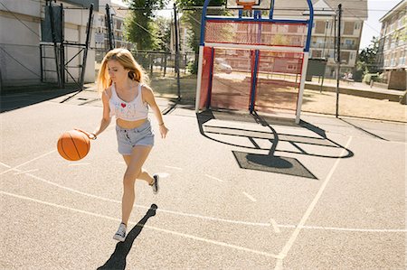 simsearch:649-09182176,k - Young woman running with ball on basketball court Fotografie stock - Premium Royalty-Free, Codice: 649-08765727