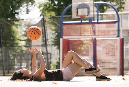 simsearch:649-09182176,k - Young woman lying on basketball court throwing ball Fotografie stock - Premium Royalty-Free, Codice: 649-08765729