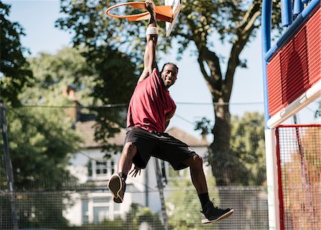 simsearch:649-09182176,k - Portrait of young male basketball player hanging from basketball hoop Fotografie stock - Premium Royalty-Free, Codice: 649-08765738