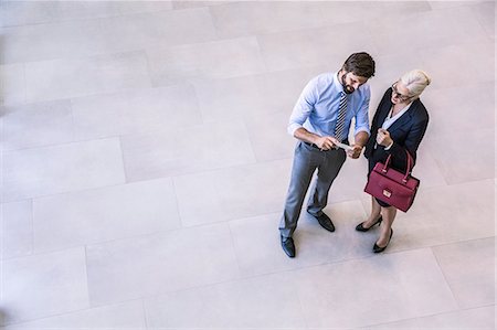 simsearch:649-08968796,k - High angle view of two businessman and woman reading smartphone text in office atrium Foto de stock - Sin royalties Premium, Código: 649-08765788