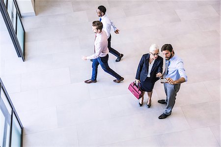 simsearch:614-08983080,k - High angle view of two businessman and woman reading smartphone text in office atrium Fotografie stock - Premium Royalty-Free, Codice: 649-08765792