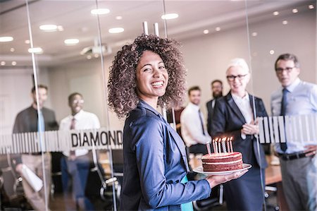 Portrait of young businesswoman carrying celebration cake into boardroom Photographie de stock - Premium Libres de Droits, Code: 649-08765826