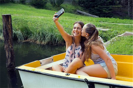 simsearch:649-08824142,k - Two young female friends taking smartphone selfie in rowing boat on lakeside Fotografie stock - Premium Royalty-Free, Codice: 649-08765998