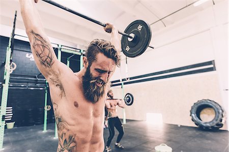pic of dumbbell tattoo - Young male cross trainer snatch lifting barbell in gym Stock Photo - Premium Royalty-Free, Code: 649-08766477