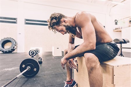 sitting in sport shorts - Exhausted male cross trainer taking a break from weightlifting in gym Stock Photo - Premium Royalty-Free, Code: 649-08766484