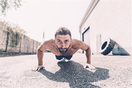 Portrait of young male cross trainer doing push-ups outside gym Stock Photo - Premium Royalty-Free, Code: 649-08766526