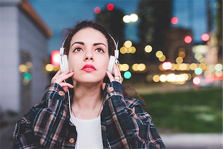 Woman wearing headphones in the city looking up, Milan Italy Stock Photo - Premium Royalty-Free, Code: 649-08824037