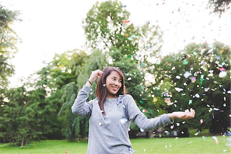 simsearch:649-08824082,k - Young woman in park throwing confetti Photographie de stock - Premium Libres de Droits, Code: 649-08824082