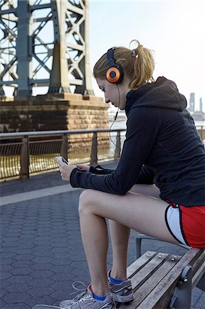 ponte williamsburg - Young woman sitting outdoors, wearing headphones, using smartphone, New York City, USA Foto de stock - Royalty Free Premium, Número: 649-08824091
