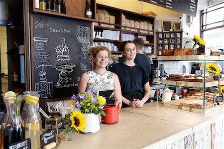 Colleagues at counter in coffee shop looking at camera smiling Photographie de stock - Premium Libres de Droits, Code: 649-08824106