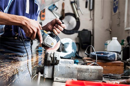 power tool - Mid section of young man using angle grinder in repair workshop Stock Photo - Premium Royalty-Free, Code: 649-08824229