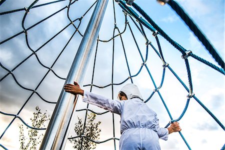 simsearch:614-09210071,k - Rear view of boy in astronaut costume climbing up playground climbing frame Stock Photo - Premium Royalty-Free, Code: 649-08824619