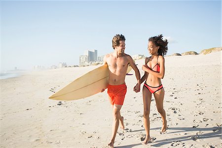 Young surfing couple running hand in hand on beach, Cape Town, Western Cape, South Africa Stock Photo - Premium Royalty-Free, Code: 649-08824626